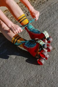 Image: hands lace a brightly coloured pair of roller-skates.