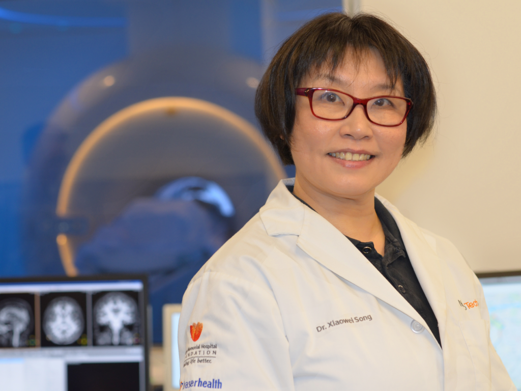 Dr. Song stands in front of imaging machine.