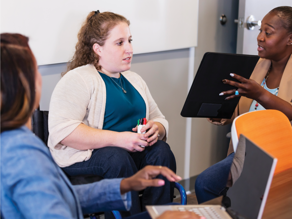 Three diverse women review a proposal on a tablet.