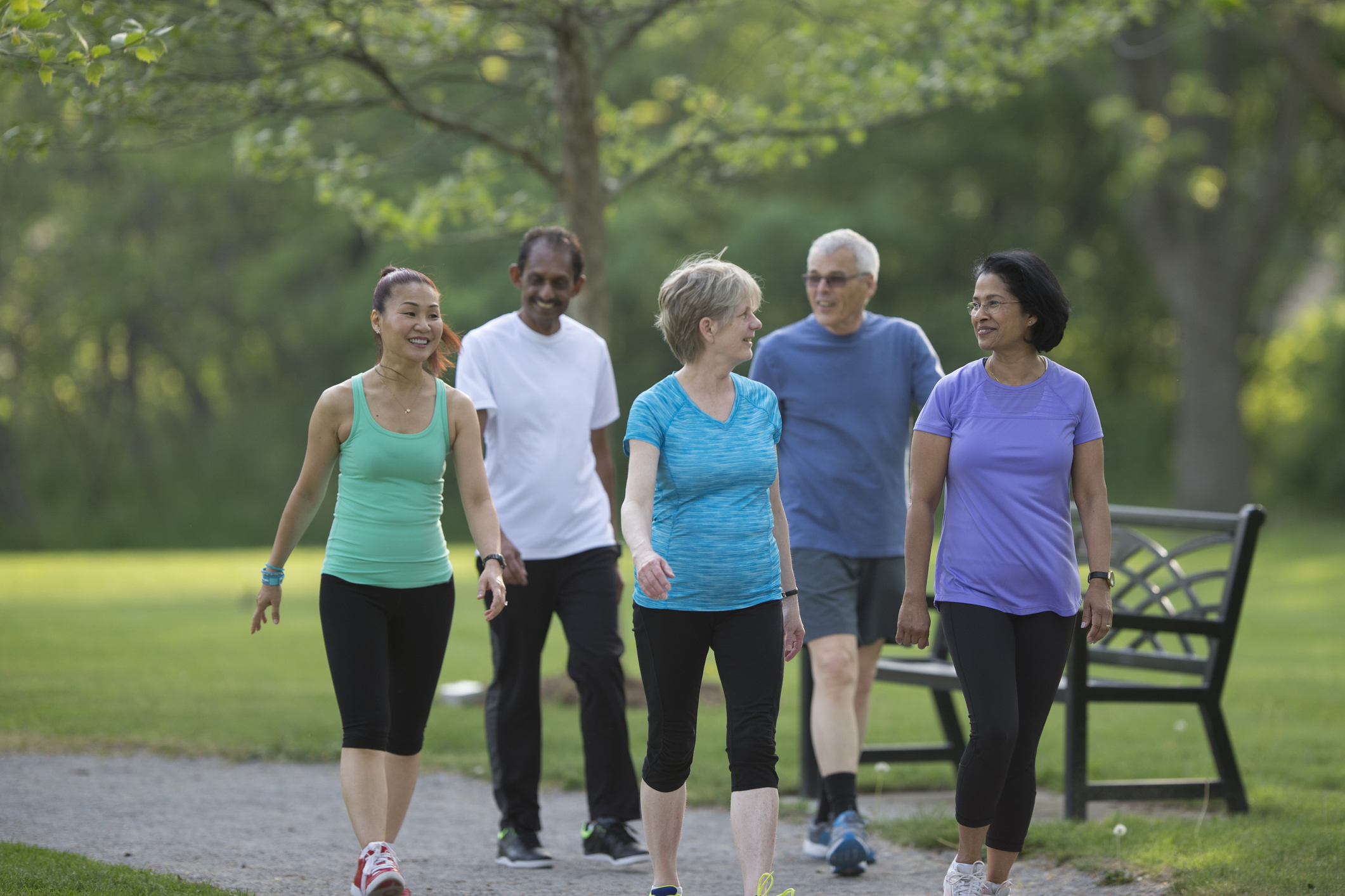 A group of senior adults are walking together on a trail through the park.