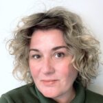 Headshot of Sarah Bennett against a white wall, with a slight smile