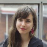 Victoria Philibert smiling at the camera, pictured against a window on an overcast day