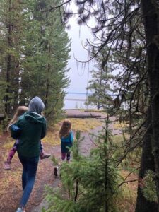 Emily Brigham walking with her daughters through a forest. She is carrying one of them.